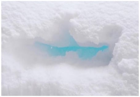 Blue-green sunlight penetrates snow and undergoes multiple scattering, while light at other wavelengths is more strongly absorbed or reflected.