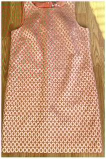 Gold-ringed patterned salmon-colored, knee-length sleeveless dress.