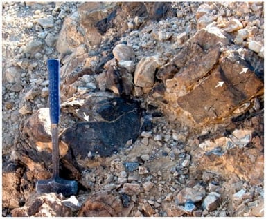 Ferritization zones (dark) in gehlenite hornfels at the type locality of shagamite near Mt. Ye’elim, Negev Desert, Israel. The white arrows indicate the ferritization zones.