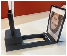 Example photograph of the described setup for device validation. The custom 3D-printed rig is shown, holding the test image and Arduino-driven LEDs opposite the fixed support for a device under test.